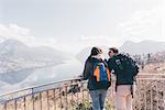 Couple looking out over mountain lakeside, Monte San Primo, Italy