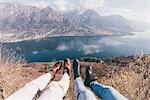 Legs of couple over mountain lakeside, Monte San Primo, Italy