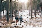 Rear view of hiking couple hiking in snowy forest, Monte San Primo, Italy