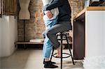 Young man hugging girlfriend from kitchen stool
