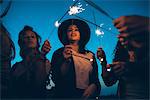 Group of friends enjoying roof party, holding lit sparklers