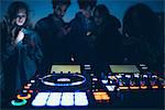 Group of people at roof party, standing around illuminated mixing desks