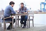 Two male designers having meeting on waterfront outside design studio