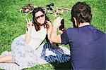 Over shoulder view of man photographing girlfriend sitting in park, Arezzo, Tuscany, Italy