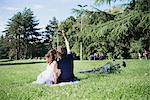 Rear view of couple taking smartphone selfie while sitting in park, Arezzo, Tuscany, Italy