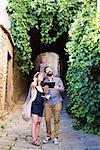 Couple with digital tablet looking up from cobbled street, Arezzo, Tuscany, Italy