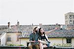 Couple sitting on wall pointing, Arezzo, Tuscany, Italy