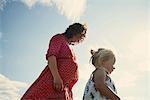 Female toddler strolling with mother against blue sky