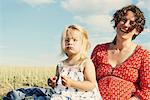 Pregnant woman sitting in field with toddler daughter