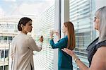 Businesswomen brainstorming ideas on glass window