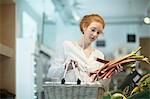Woman in shop holding shopping basket and rhubarb