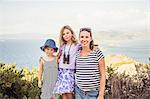 Portrait of mother standing with two daughters, near sea, smiling