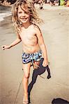 Young girl running on beach, smiling