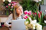 Florist worker in flower shop, using laptop, bored expression