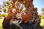 Boy blowing bubbles in park