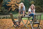 Portrait of two sisters sitting on patio table in autumn garden