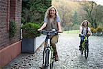 Two sisters cycling together in park