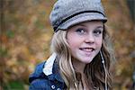 Portrait of blond girl in baker boy cap listening to earphone music