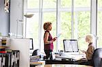 Two female interior designers discussing swatch at office desk