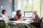 Three female designers having working lunch meeting in office