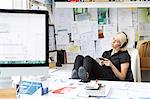 Female designer with feet up at desk listening to headphone music