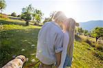 Romantic young couple walking dog in sunlit rural field, Majorca, Spain