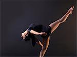Low key shot of young female dancer bending backwards whilst standing on one leg