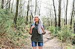 Mature woman with long grey hair looking up from forest, Scandicci, Tuscany, Italy