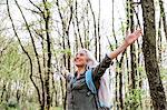 Mature woman with long grey hair with open arms in forest, Scandicci, Tuscany, Italy