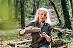 Mature female backpacker pouring drinks flask in forest, Scandicci, Tuscany, Italy