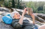 Mature female backpacker reclining on rock in forest, Scandicci, Tuscany, Italy