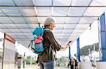 Mature female backpacker looking at smartphone in bus station, Scandicci, Tuscany, Italy