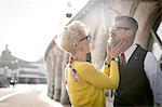 1950's vintage style mature woman cupping boyfriend's chin at coast