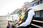 1950's vintage style couple looking out from beach bench