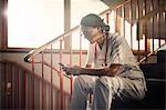 Female doctor sitting on stairs with smartphone