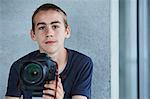 Portrait of teenage boy holding digital camera
