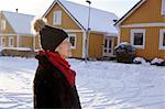 Senior woman standing in front of house in winter