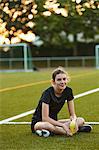 Teenage girl sitting on playing field