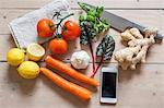 Smartphone and vegetables on table