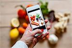 Woman photographing vegetables with smartphone