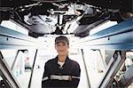 Female mechanic standing with arms crossed under a car