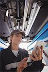 Female mechanic using digital tablet under a car