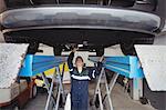 Female mechanic examining a car with flashlight