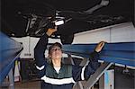 Female mechanic examining a car with flashlight