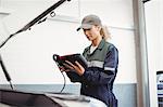 Female mechanic using electronic diagnostic device