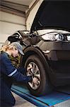 Female mechanic examining a car wheel