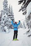 Skier standing with ski on snowy landscape