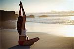 Beautiful woman performing yoga on beach