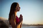 Beautiful woman meditating on beach