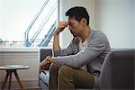 Tensed man sitting on sofa in living room